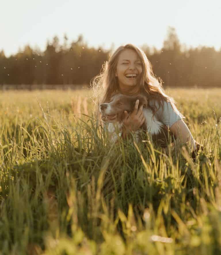Woman in White Long Sleeve Shirt Sitting on Green Grass Field